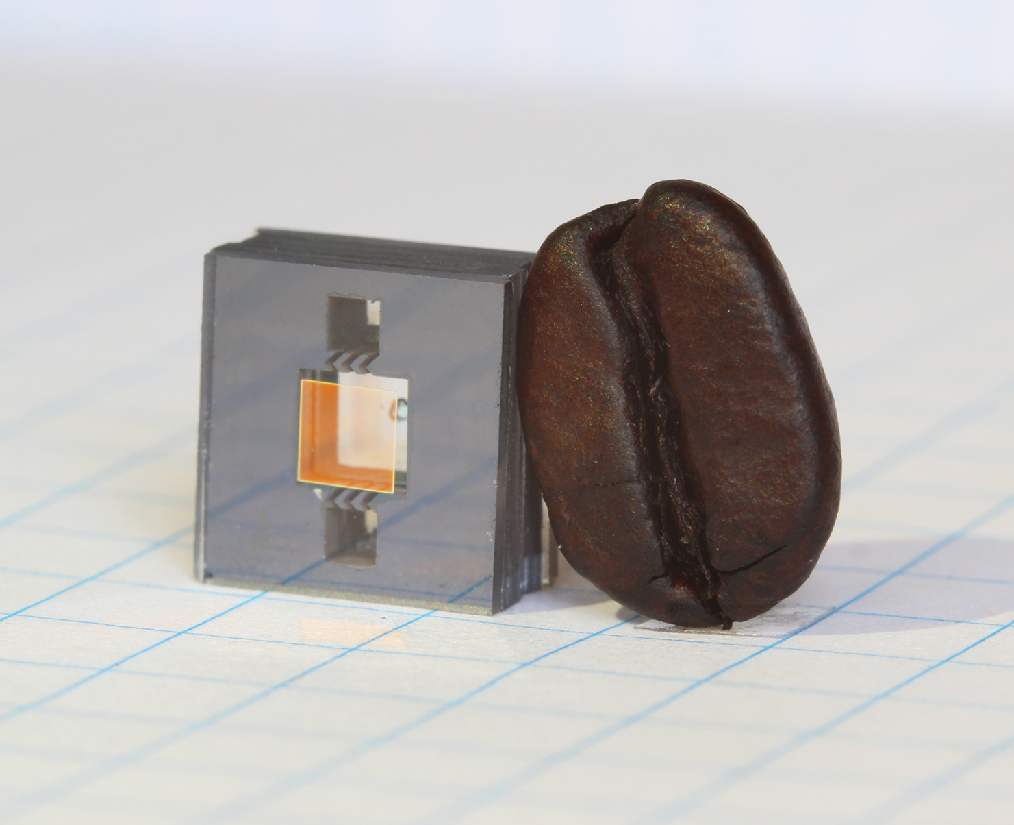 NIST chip-scale atomic clock component next to coffee bean for scale